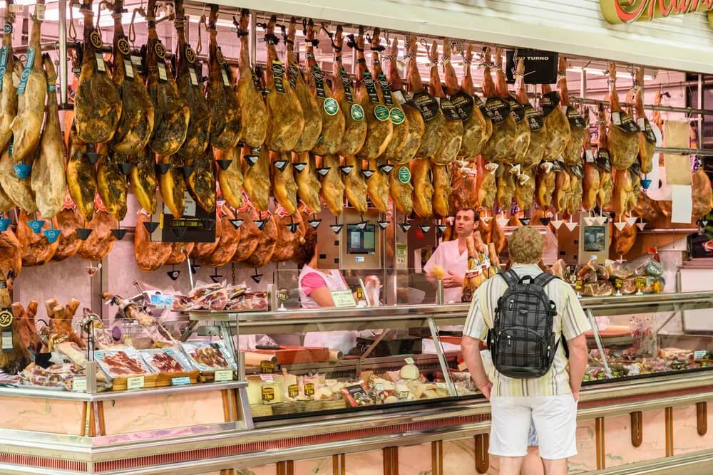 turista olha para os jamons num mercado tradicional