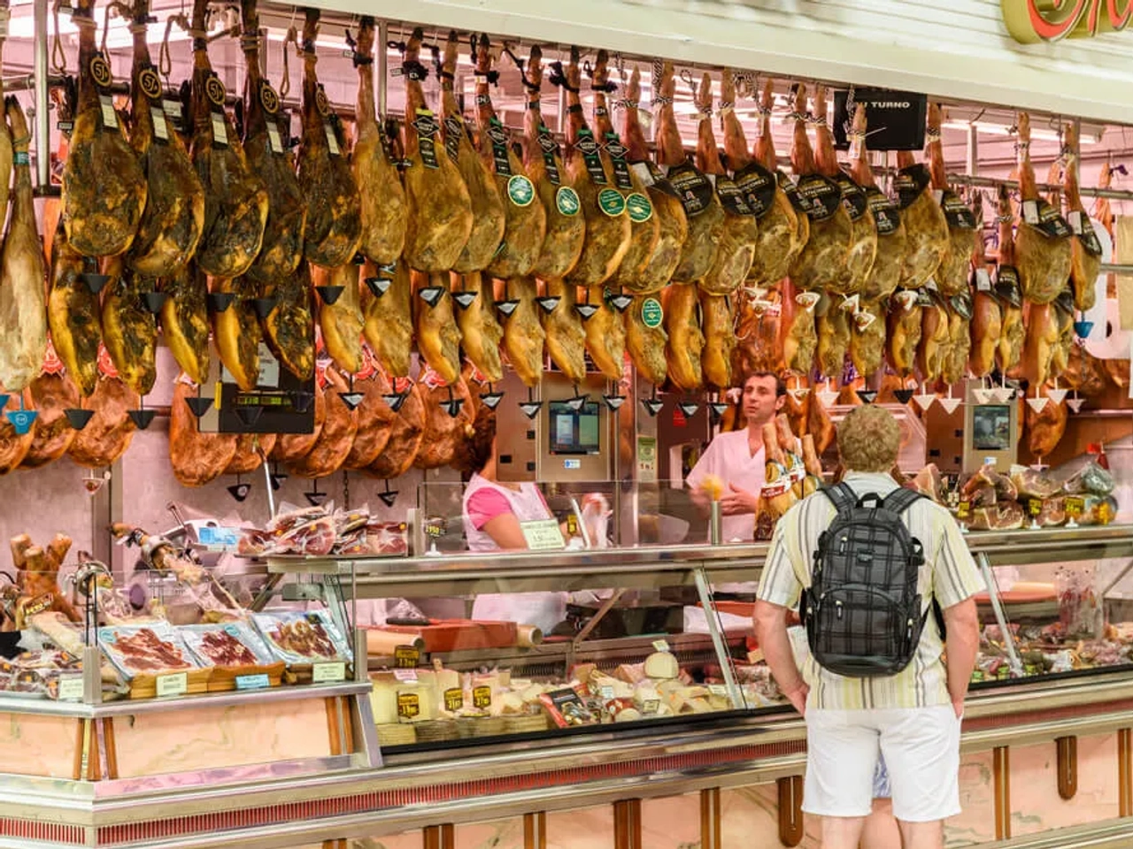 turista olha para os jamons num mercado tradicional