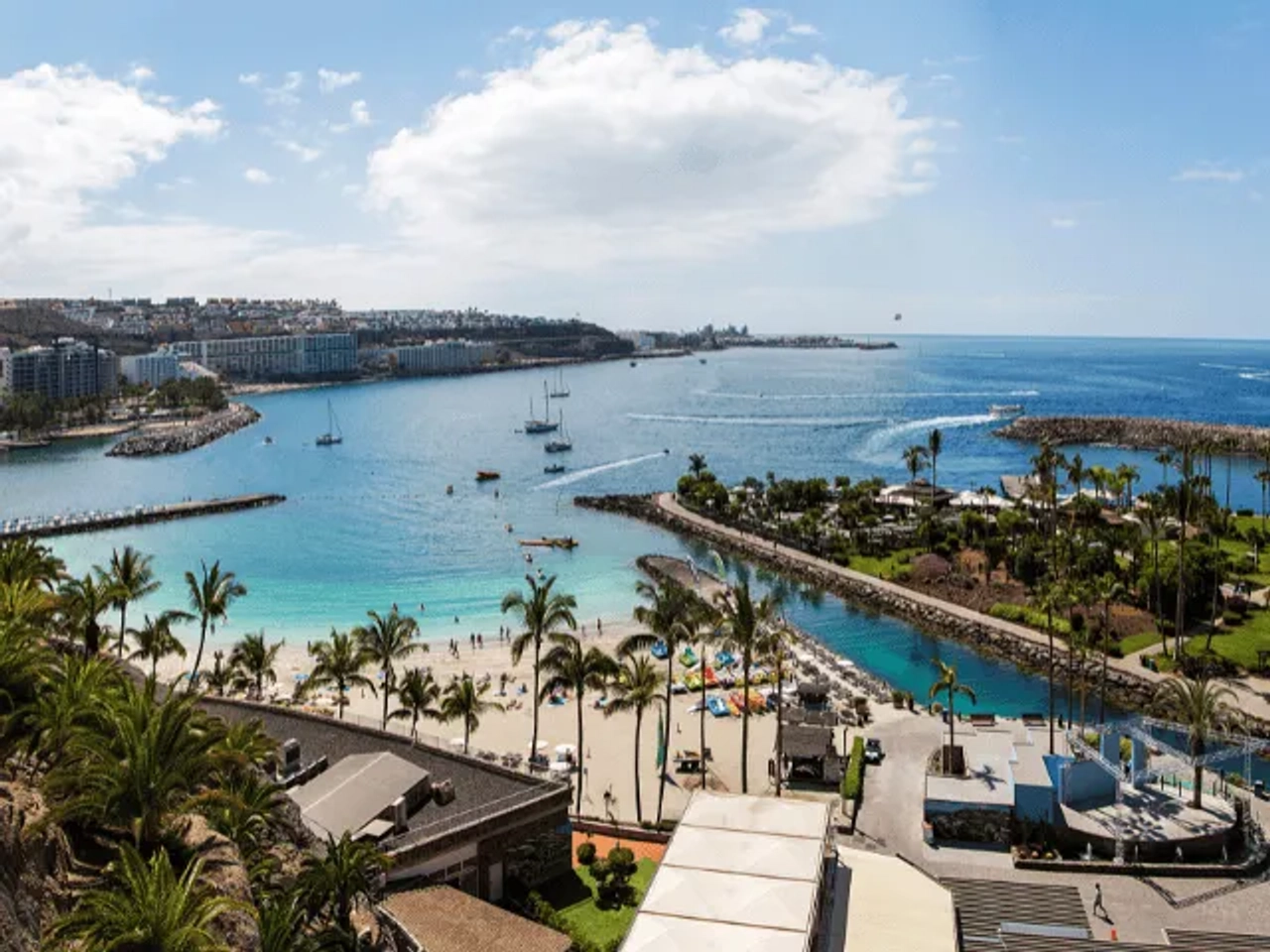 vista aerea de barcos, plameiras, casas e pessoas junto à praia de agua azul turquesa em gran canaria nas ilhas canarias