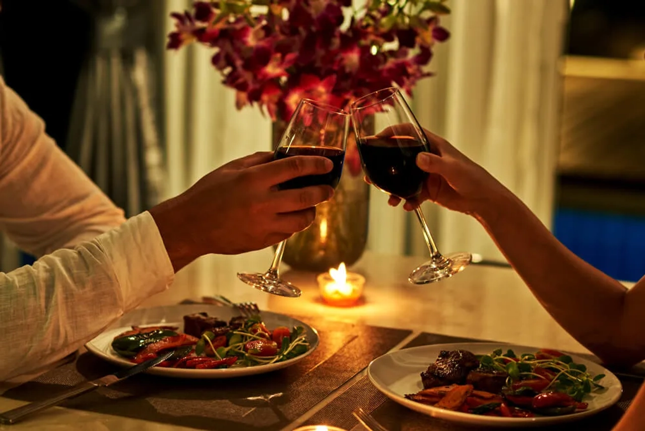 casal brinda com copo de vinho num jantar romantico