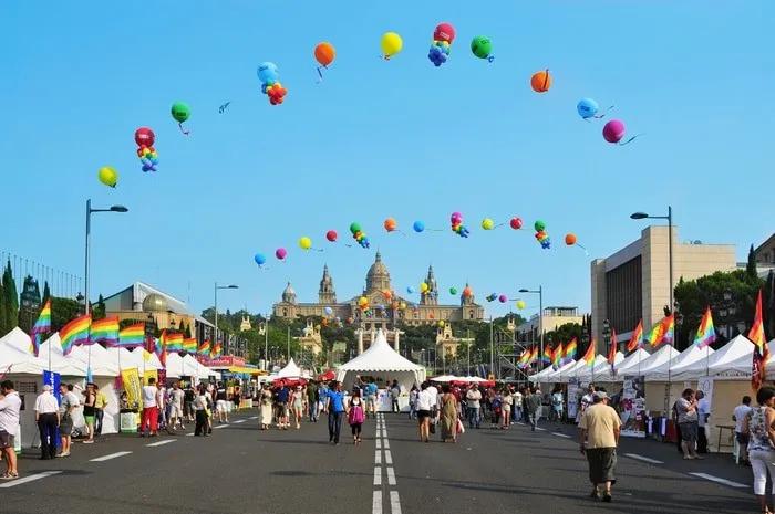 Celebración del Día del Orgullo Gay con globos y puestos en una calle festiva.