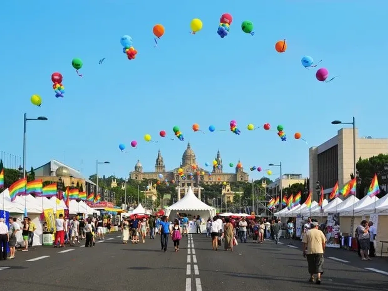 Celebración del Día del Orgullo Gay con globos y puestos en una calle festiva.