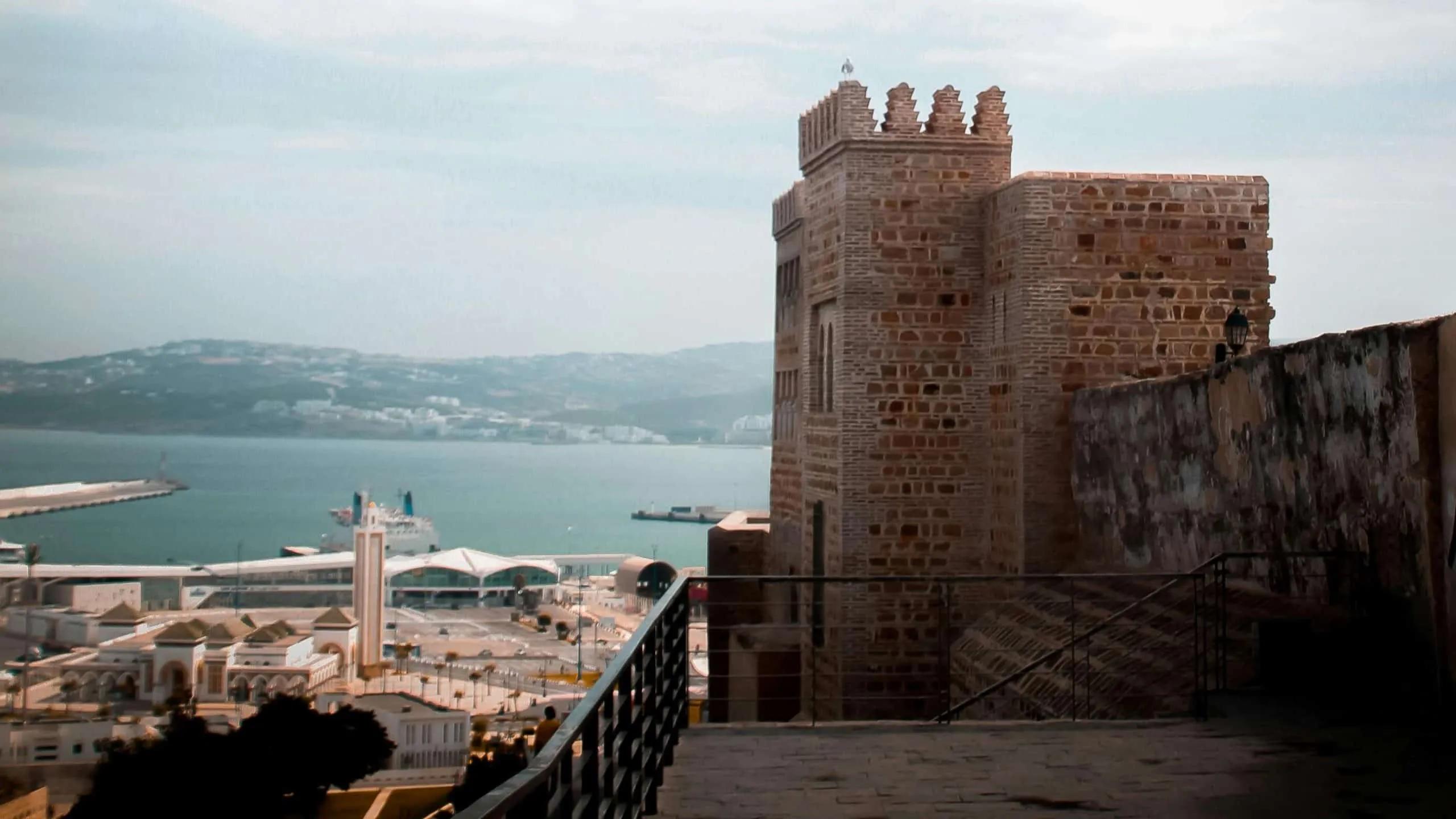 Vista da cidade de Tânger com um castelo e o mar ao fundo.