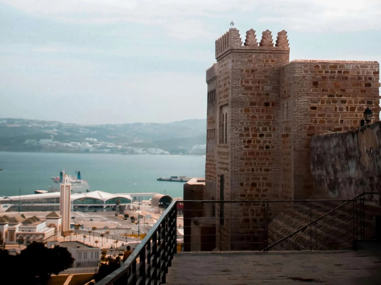 Vista da cidade de Tânger com um castelo e o mar ao fundo.