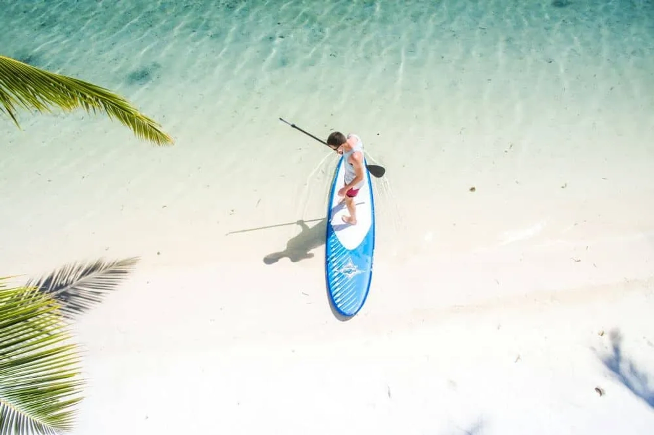 Persona practicando paddle surf en aguas cristalinas de una playa en Maldivas.