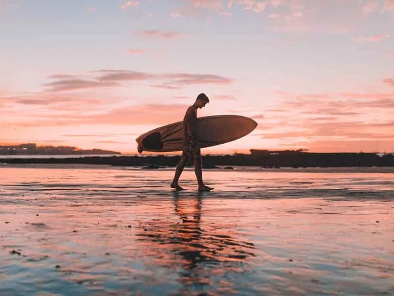 homem com prancha de surf na mão junto ao mar na costa rica