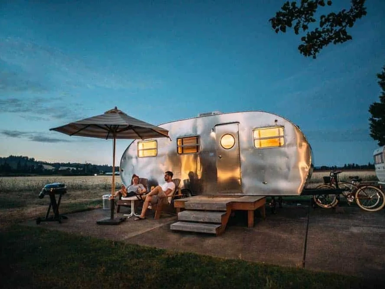 duas pessoas do lado de fora de uma autocaravana ao anoitecer