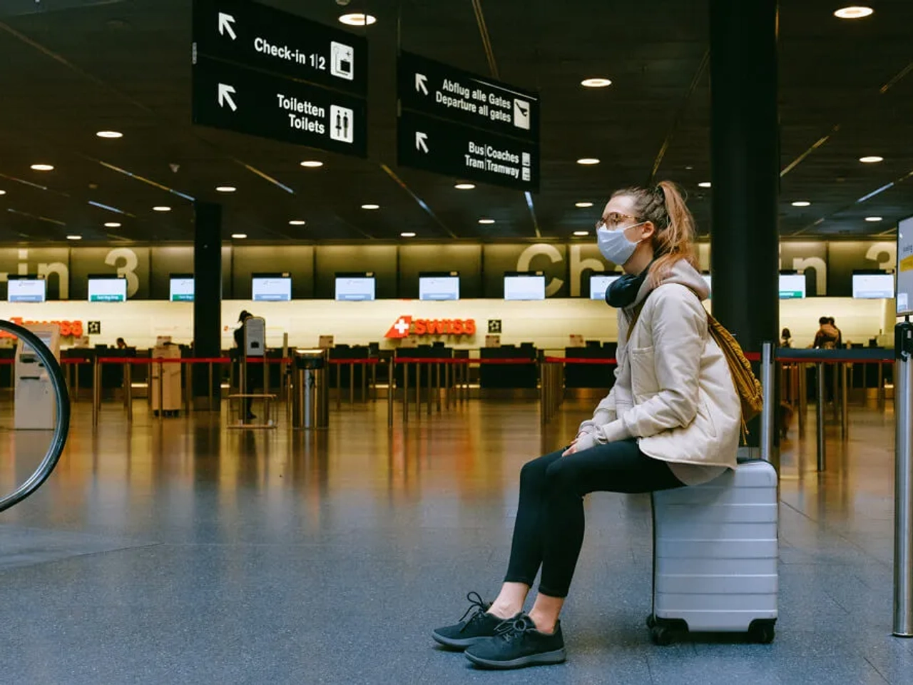 mulher de mascara espera num aeroporto