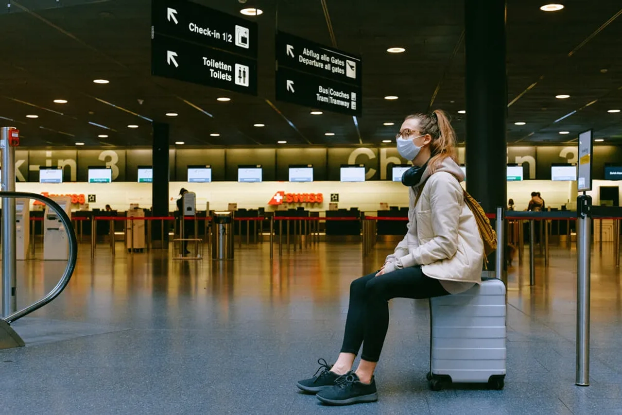 mulher de mascara espera num aeroporto