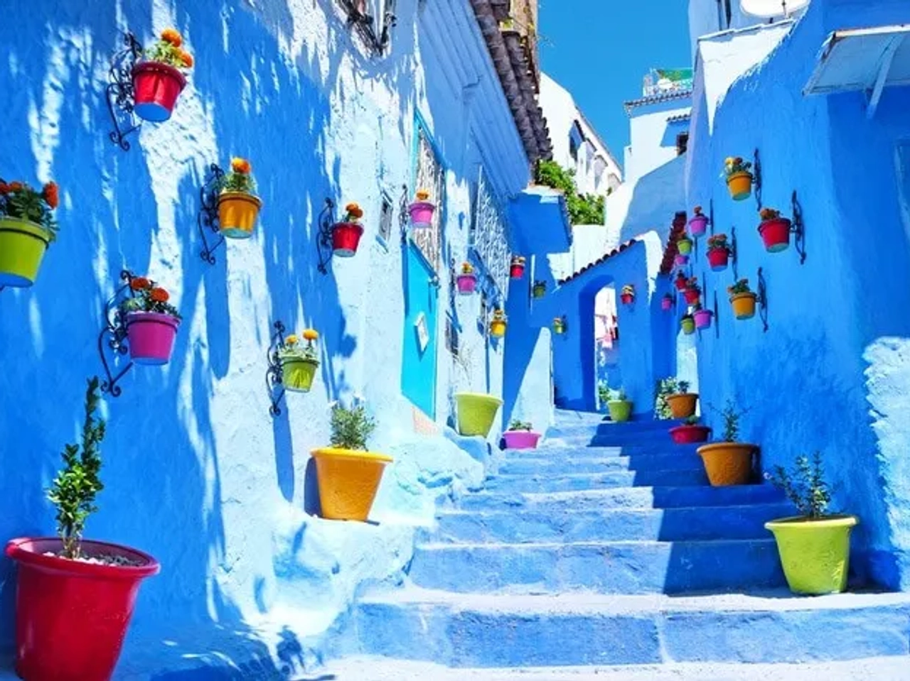 Calle colorida con macetas en una ciudad azul de Marruecos.