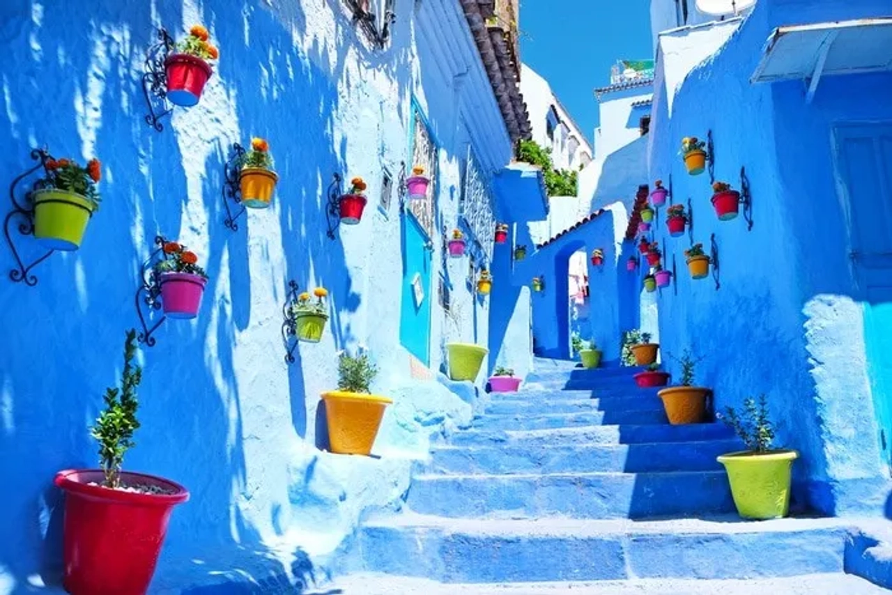 Calle colorida con macetas en una ciudad azul de Marruecos.