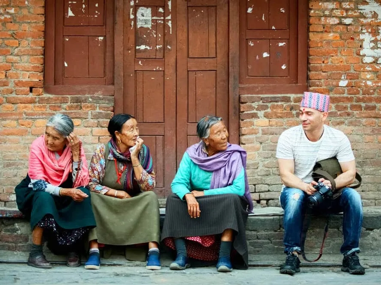 turista a falar com três locais sentados numas escadas