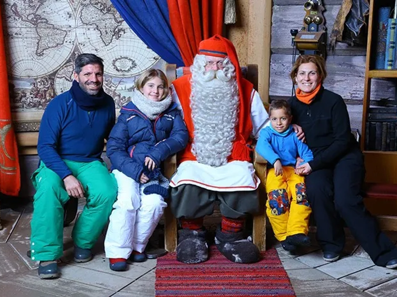 Familia viajera posando con Santa Claus en un ambiente invernal.