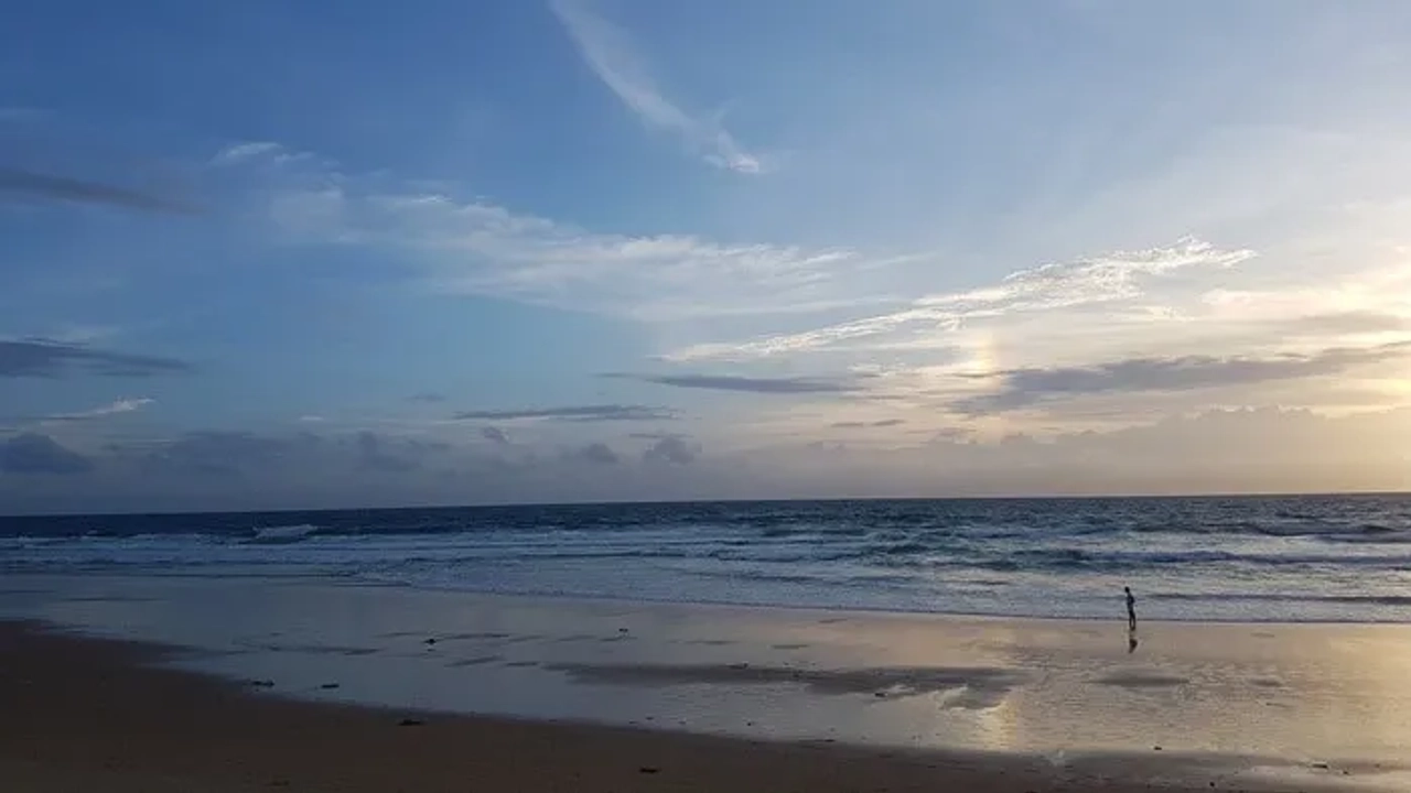 Playa tranquila al atardecer, con una persona caminando cerca del agua.