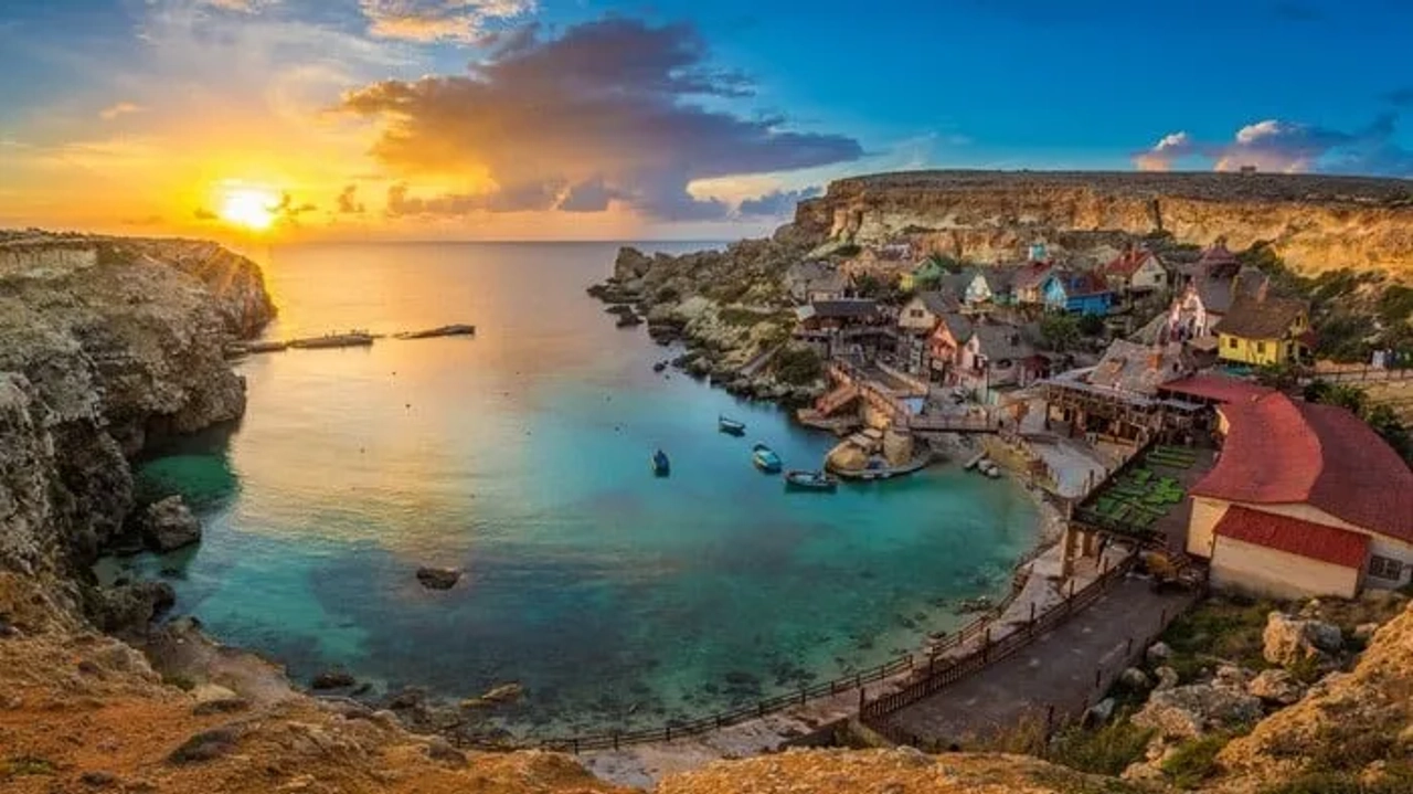 Pôr do sol sobre uma baía com casas coloridas e barcos em Malta.