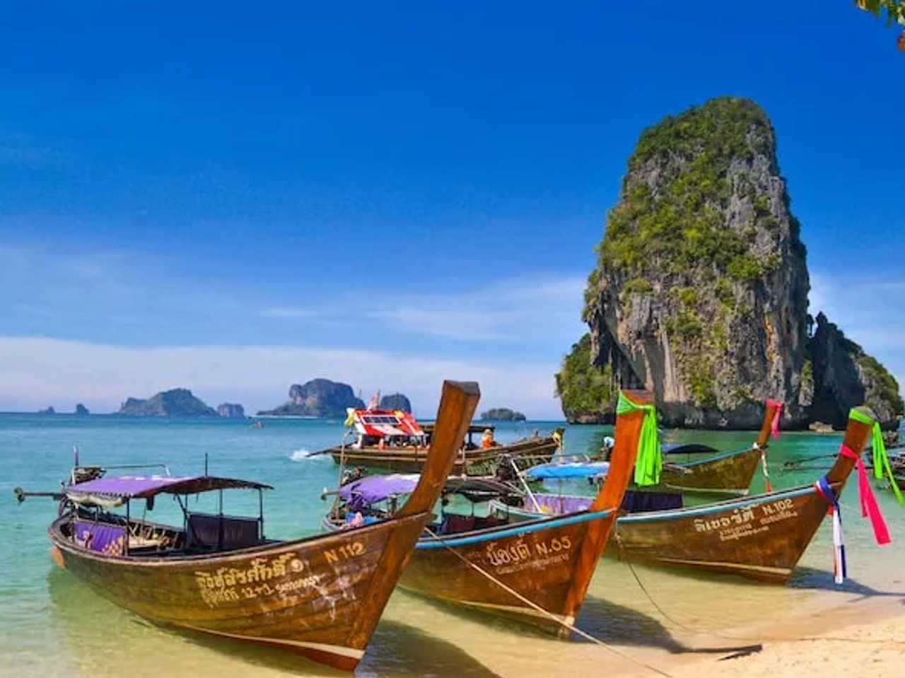 three boats on an island with blue water in thailand