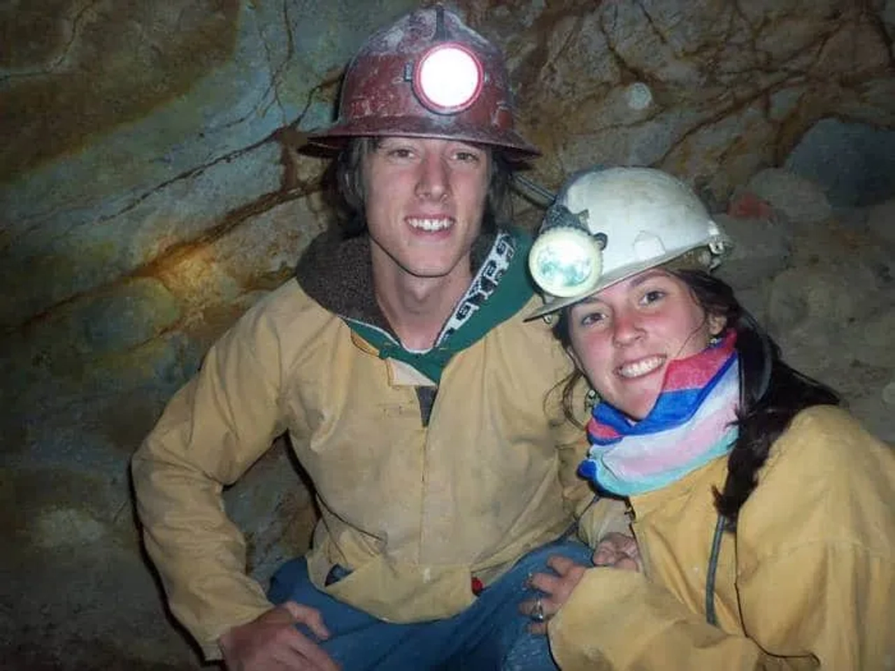 Pareja de viajeros en una mina, usando cascos y ropa de trabajo.