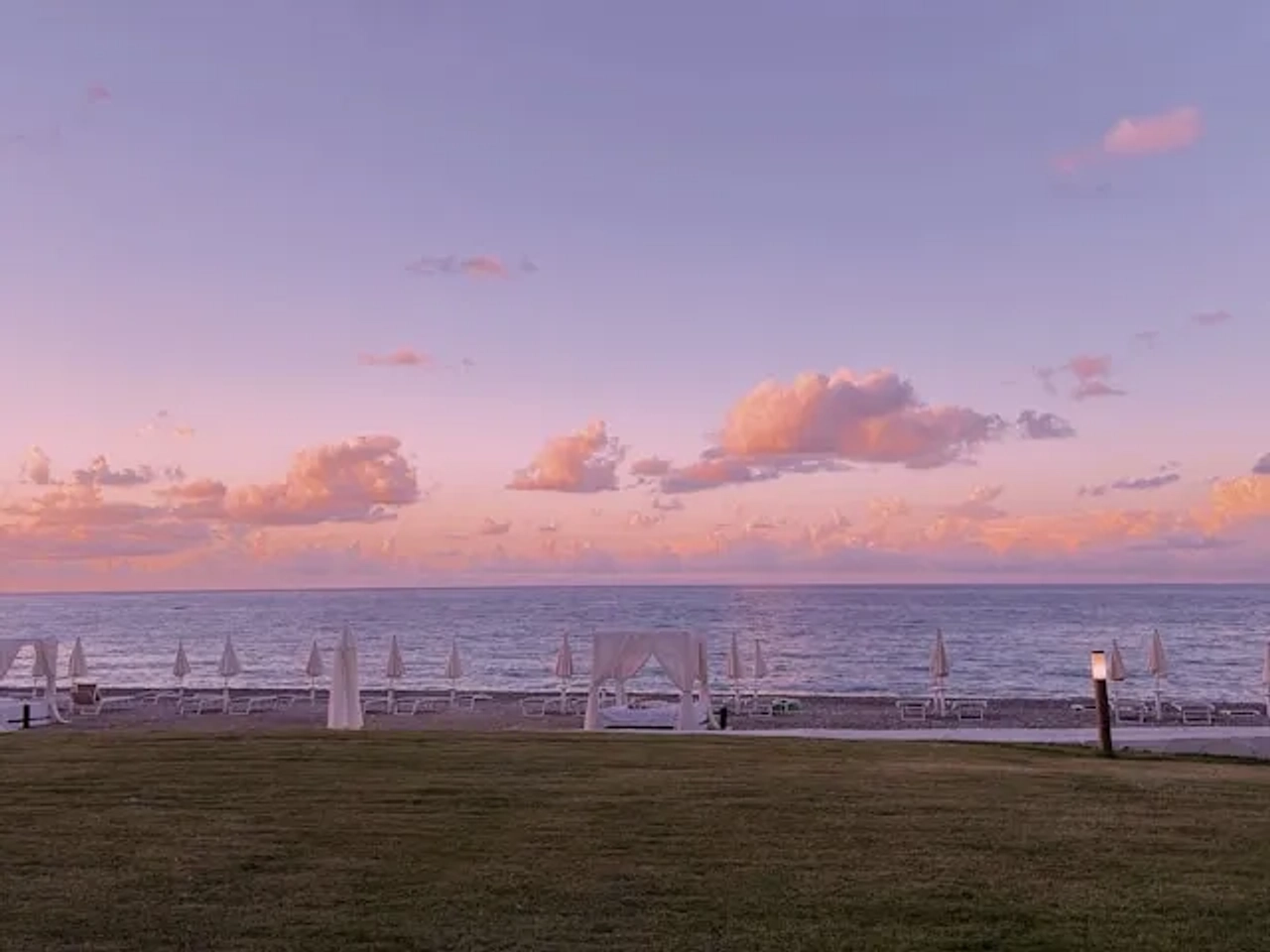 vista de uma praia com guarda-sois e ceu rosa clarinho em Palermo em Italia