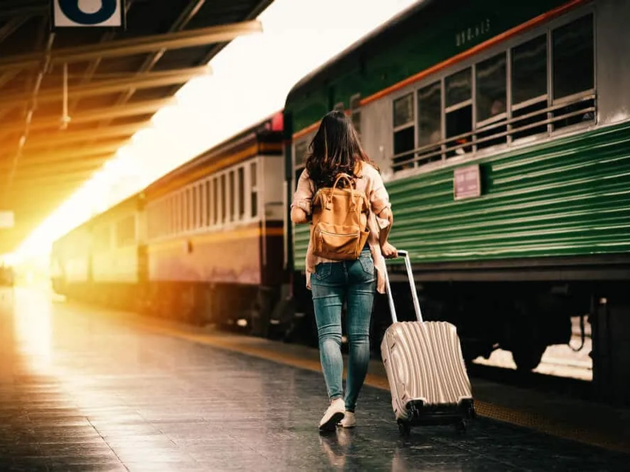 mulher viajante com mala ao lado de um comboio verde