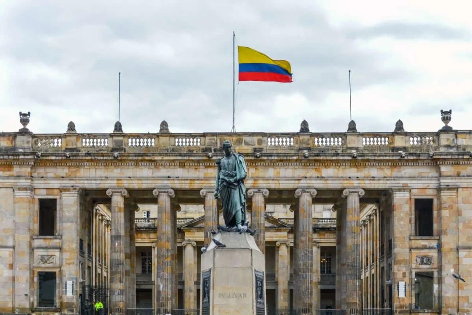 Edificio del Congreso de Colombia con estatua y bandera nacional ondeando.