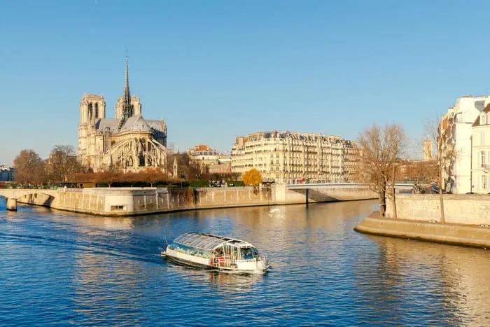 Barco navegando por el río Sena, con la catedral de Notre-Dame al fondo.