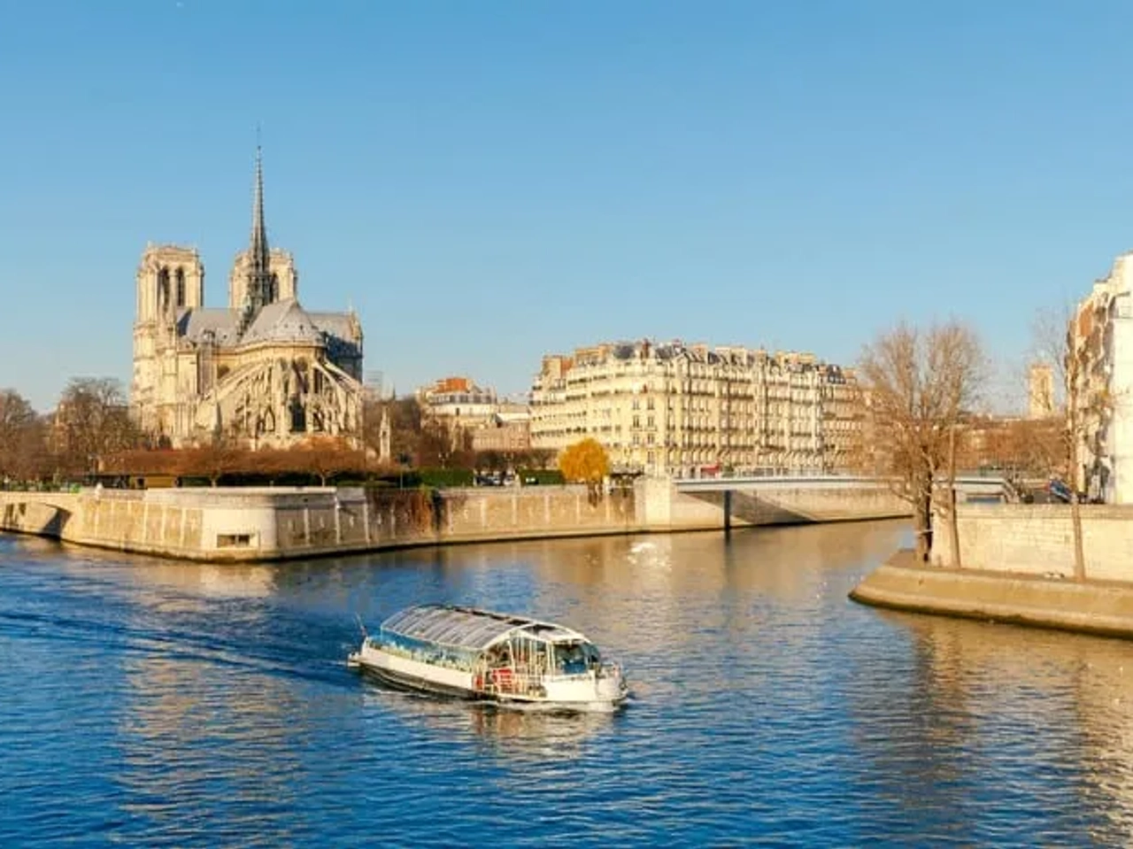 Barco navegando por el río Sena, con la catedral de Notre-Dame al fondo.