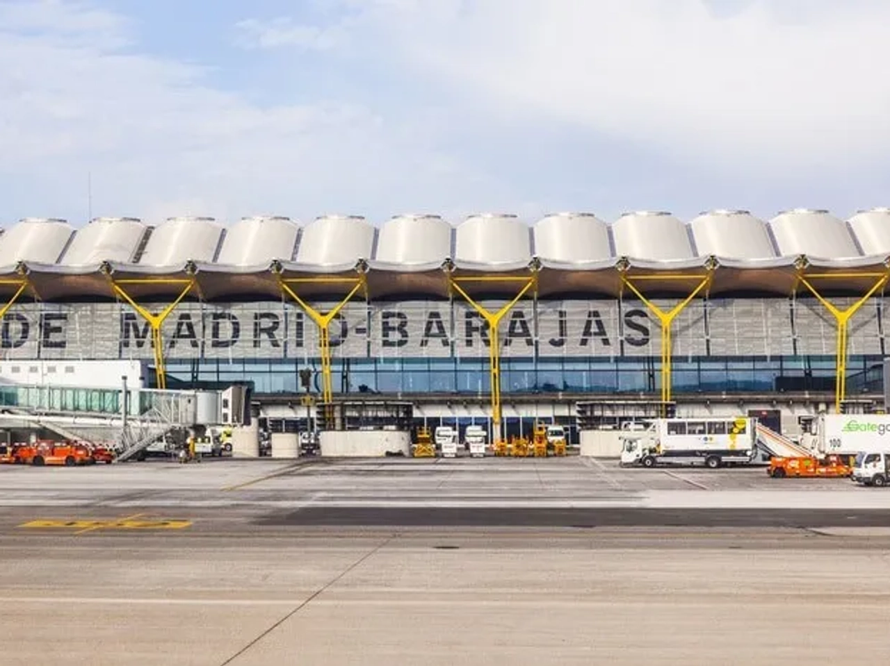 Edificio del aeropuerto de Madrid-Barajas con aviones y vehículos de servicio.