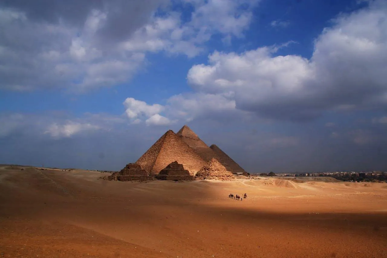 Pirâmides do Egito em um deserto sob um céu nublado.