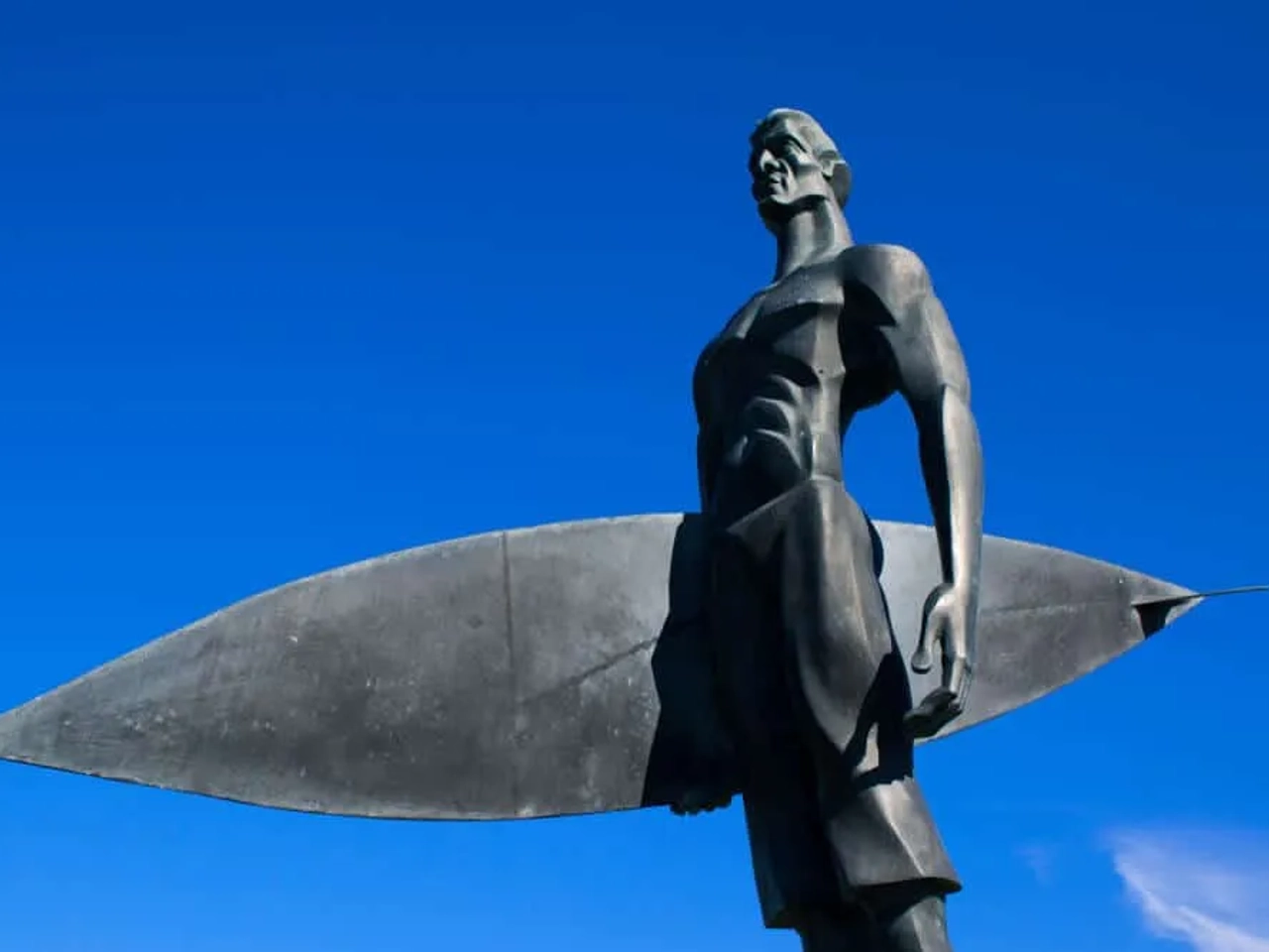 estatua dedicada ao surf em fundo de ceu azul