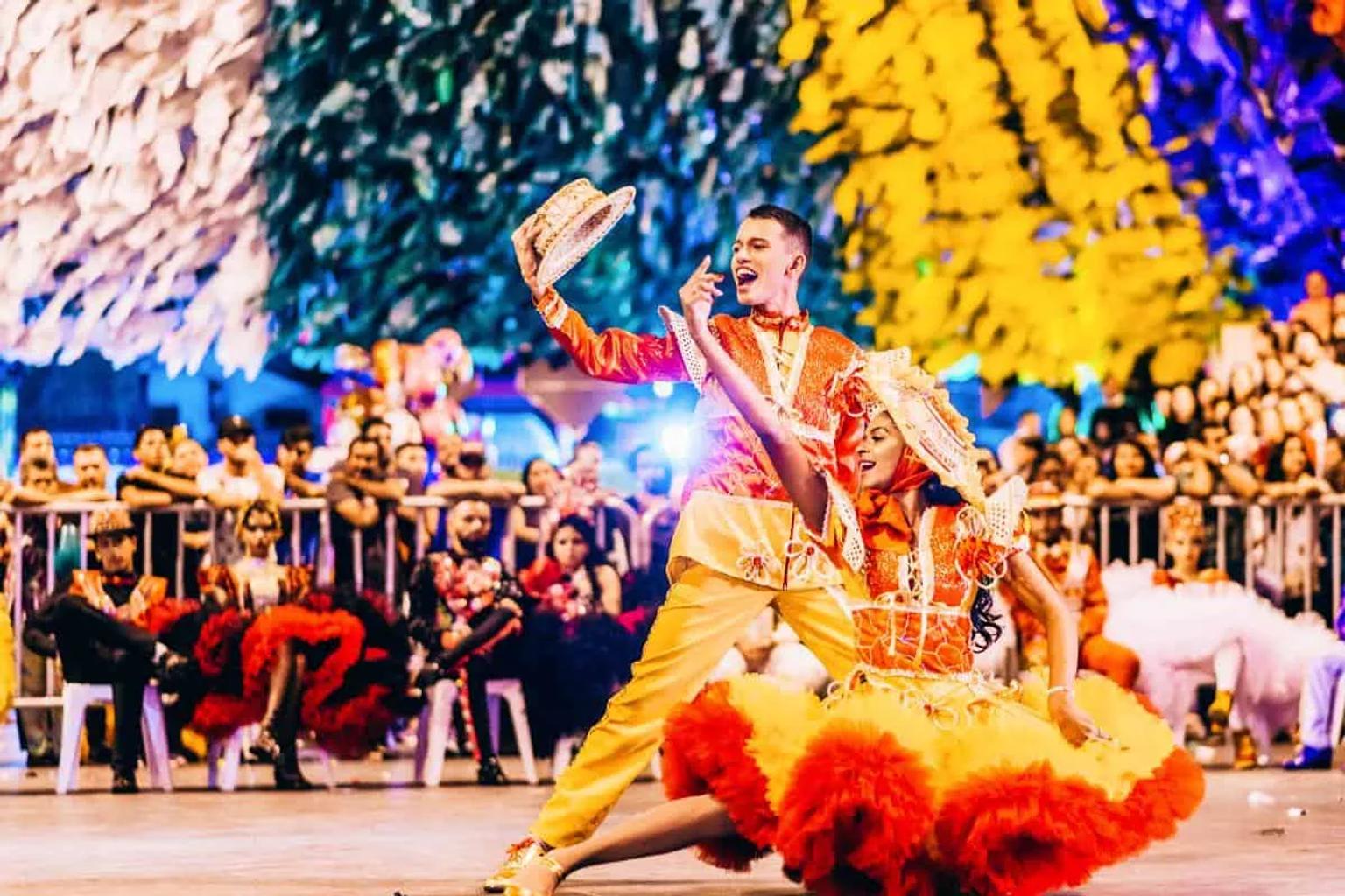 Pareja bailando en el Carnaval de Río de Janeiro, con trajes coloridos y público animado.