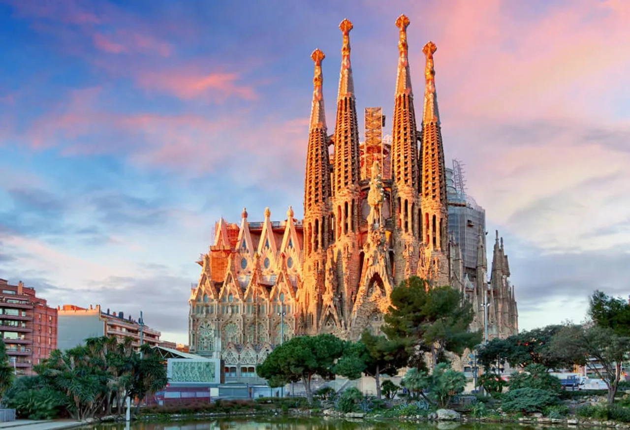 Sagrada Família iluminada ao pôr do sol, destacando suas torres e detalhes arquitetônicos.