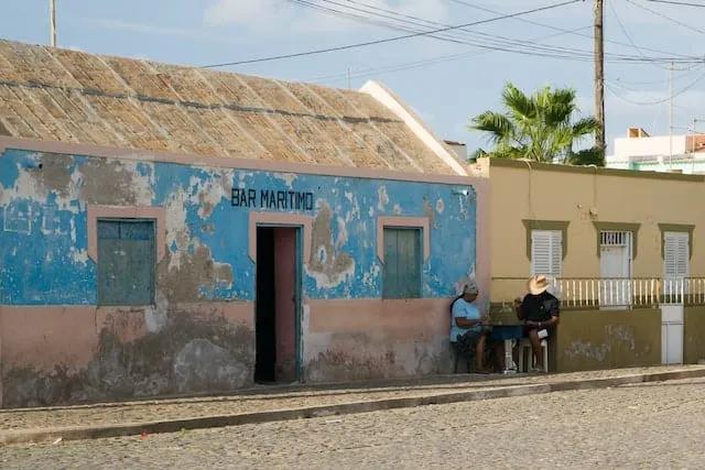 dois homens sentados em frente a uma casa na ilha do sal em cabo verde