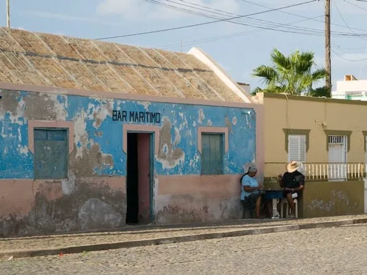 dois homens sentados em frente a uma casa na ilha do sal em cabo verde