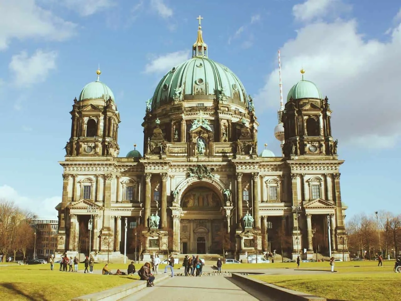 Catedral de Berlim com sua cúpula verde e pessoas no parque ao redor.