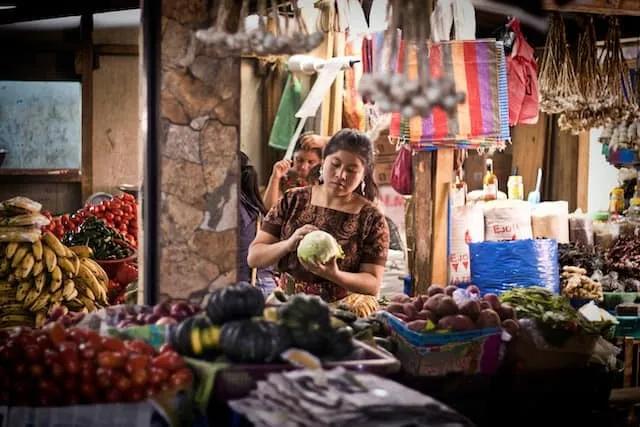 mulher a pegar num melão num mercado de frutas em guatemala