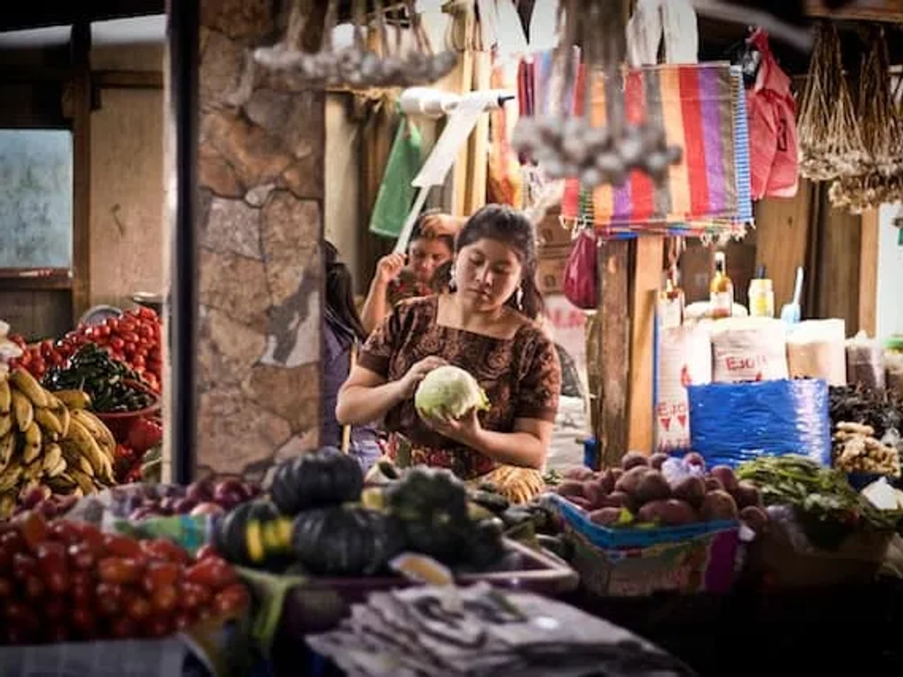 mulher a pegar num melão num mercado de frutas em guatemala