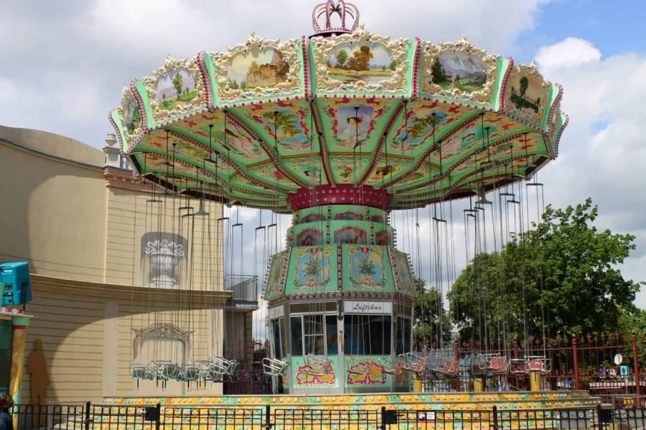 Carrossel colorido em parque de diversões, com cadeiras suspensas e decoração vibrante.