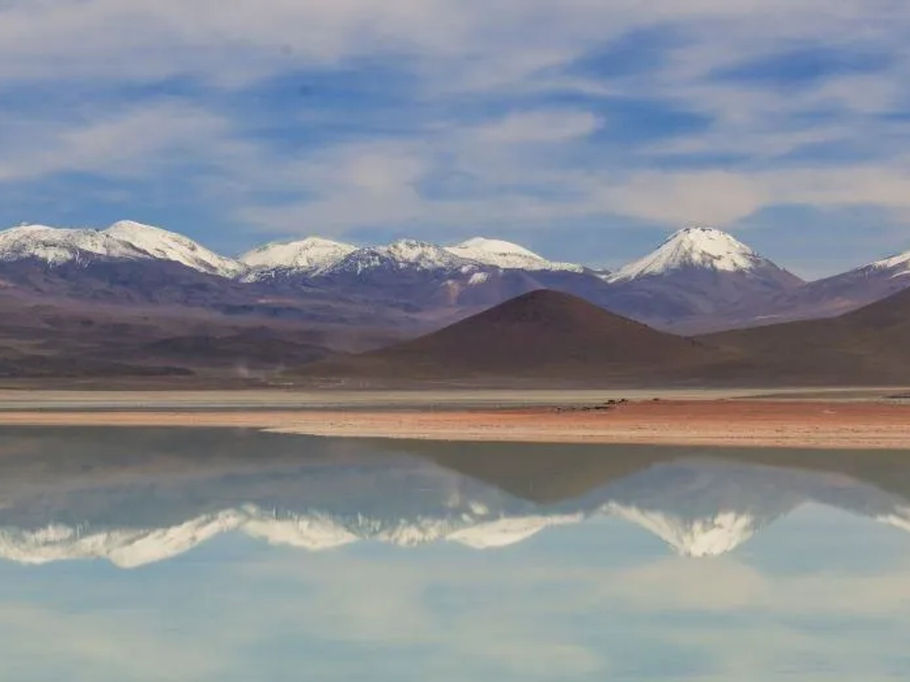 Paisaje montañoso con reflejos en un lago, representando la belleza de Bolivia.