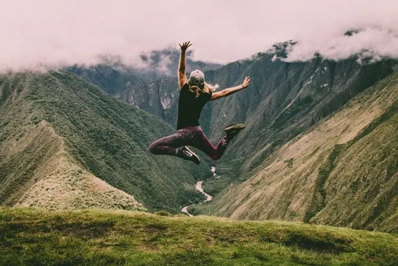 senhora a saltar no meio de montanhas verdes nos Andes