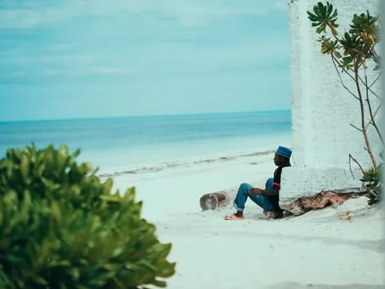 pessoa sentada na areia a observar o mar