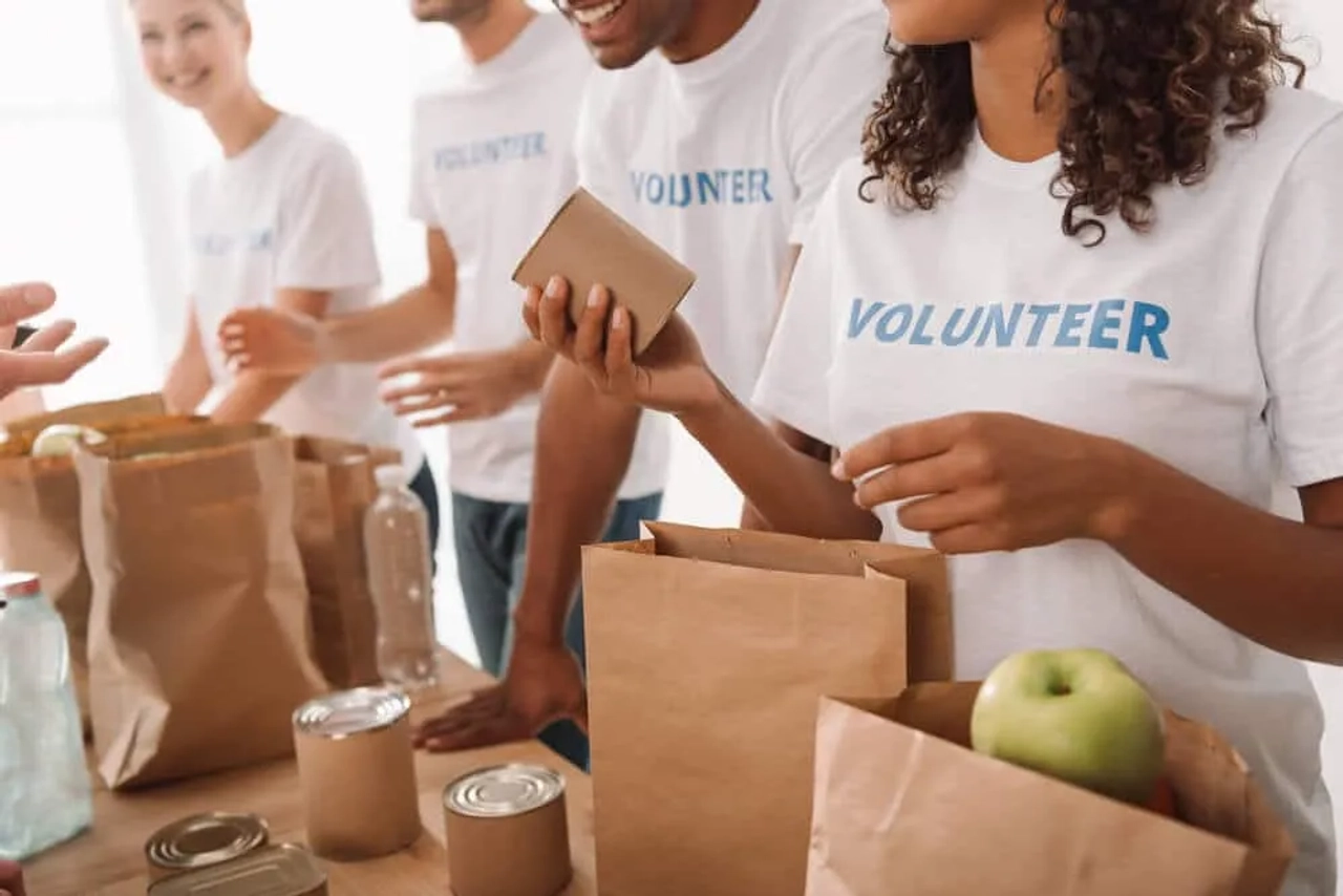 jovens com camisolas de voluntarios empacotam comida