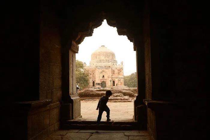 Niño caminando hacia un monumento histórico a través de un arco.