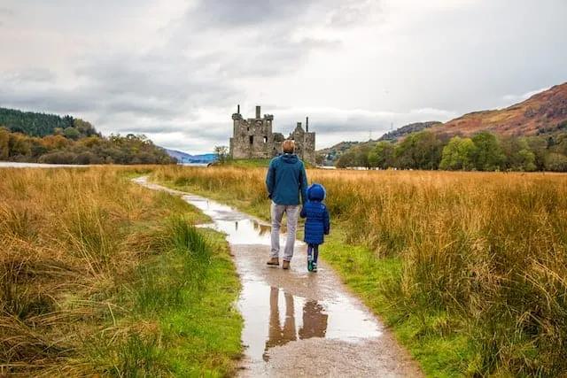 pai e filho a andarem em direção ao Kilchurn Castle na Escócia