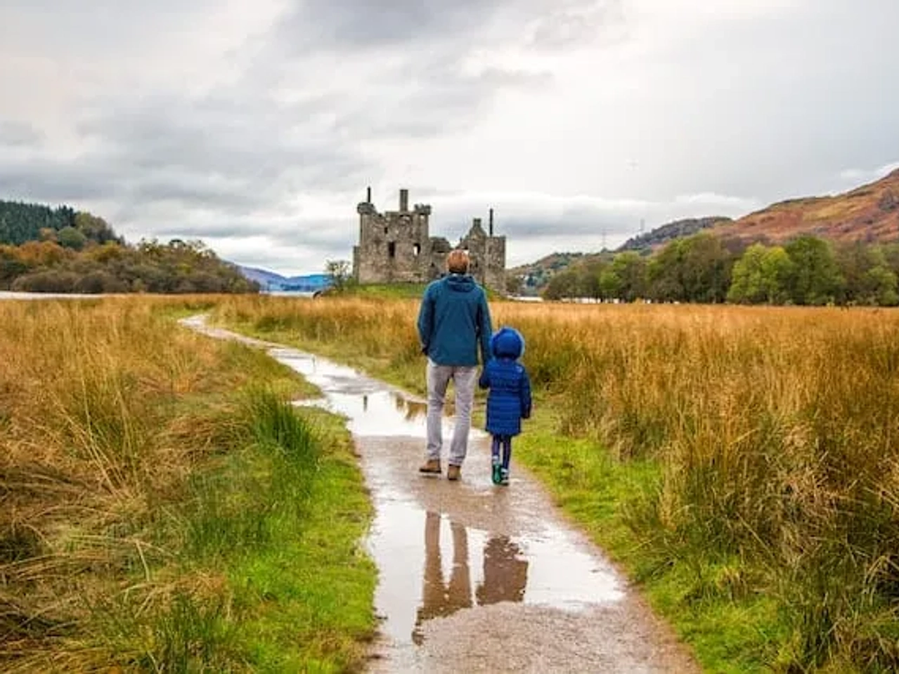 pai e filho a andarem em direção ao Kilchurn Castle na Escócia