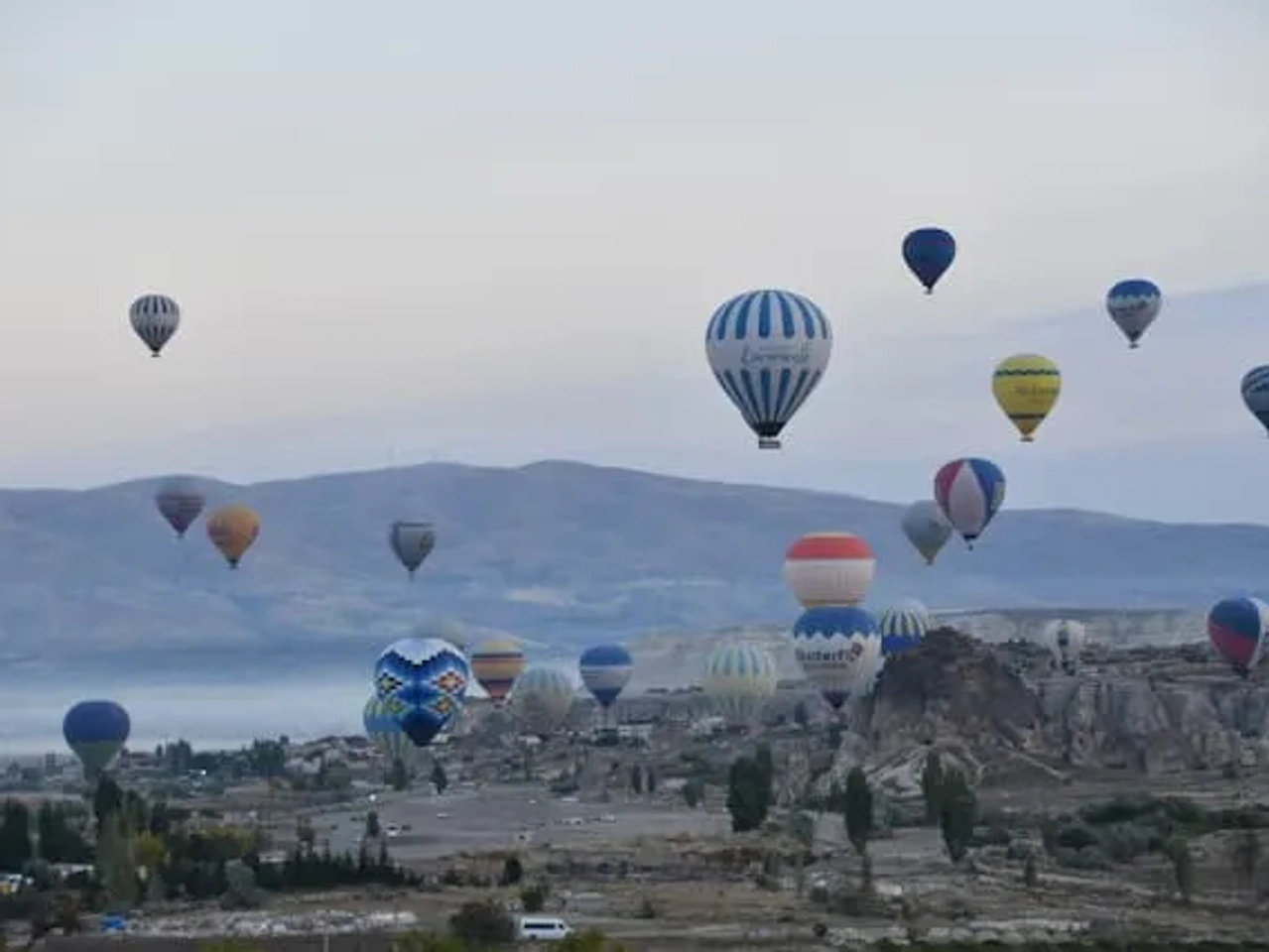 vários balões de ar quente coloridos a sobrevoar a capadócia na turquia ao final da tarde