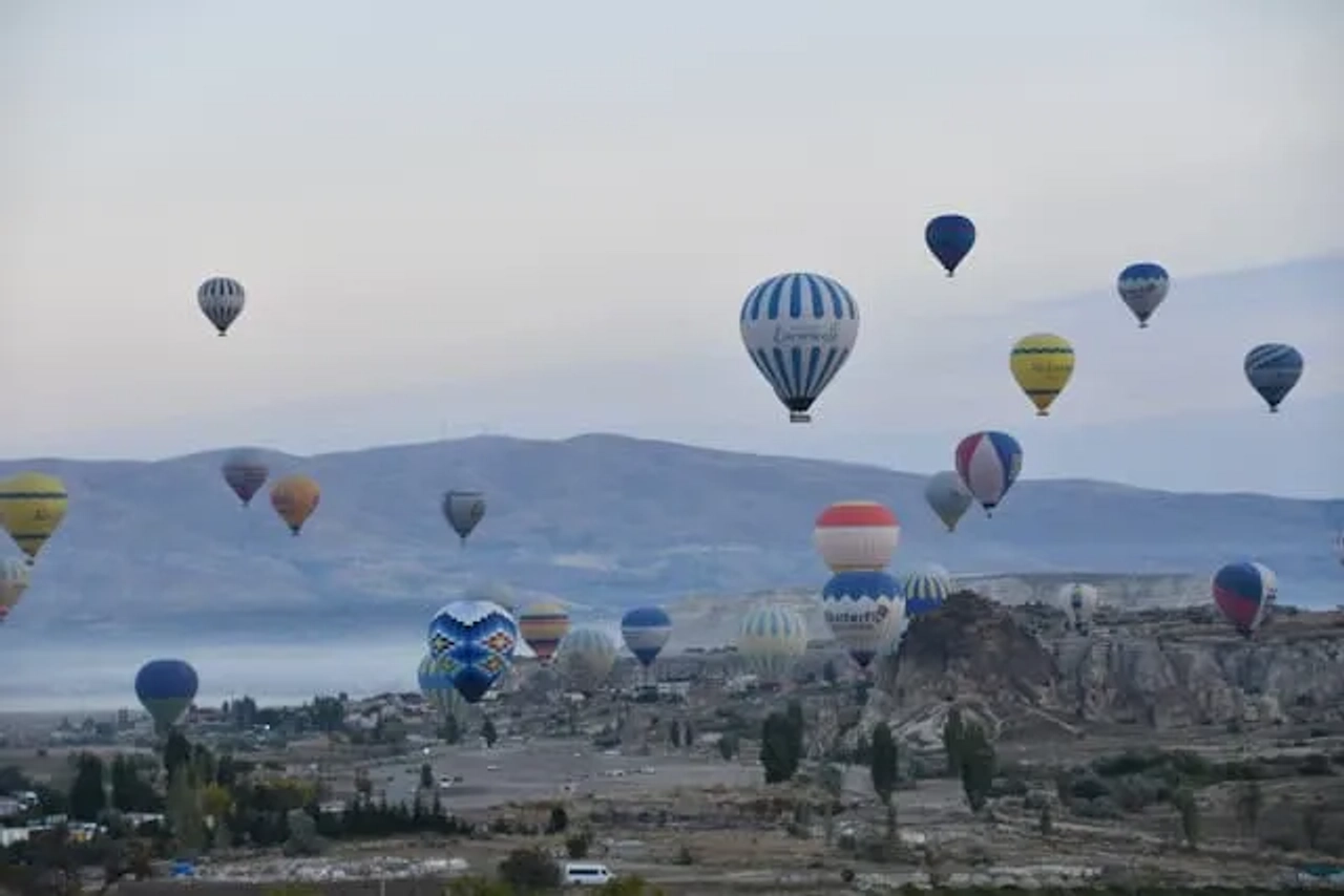 vários balões de ar quente coloridos a sobrevoar a capadócia na turquia ao final da tarde