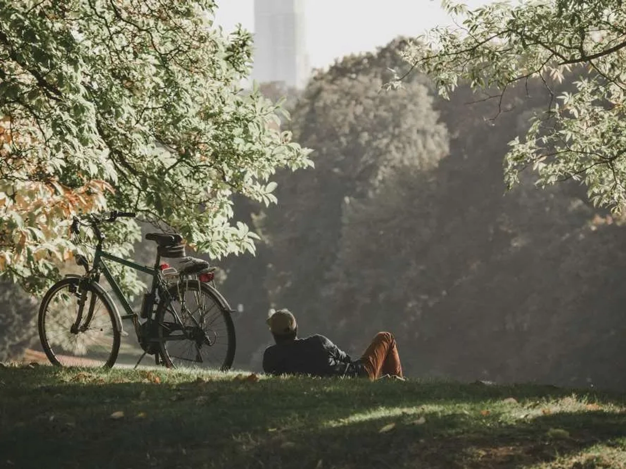 Hombre descansando junto a su bicicleta en un parque de Bélgica.