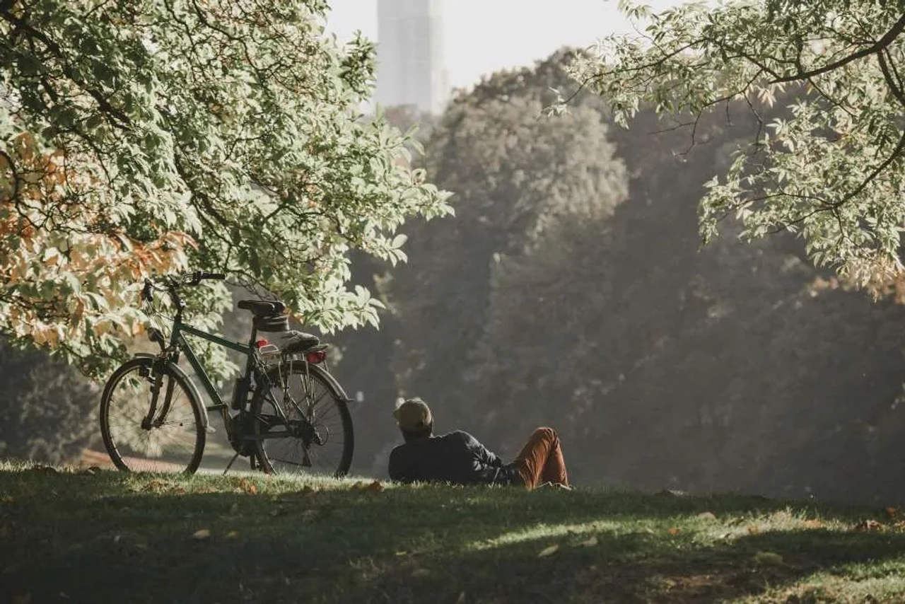 Hombre descansando junto a su bicicleta en un parque de Bélgica.
