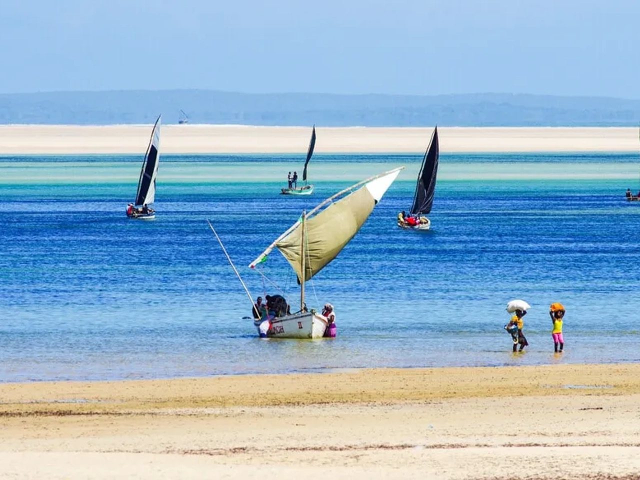 pessoas e barcos tradicionais numa praia de moçambique