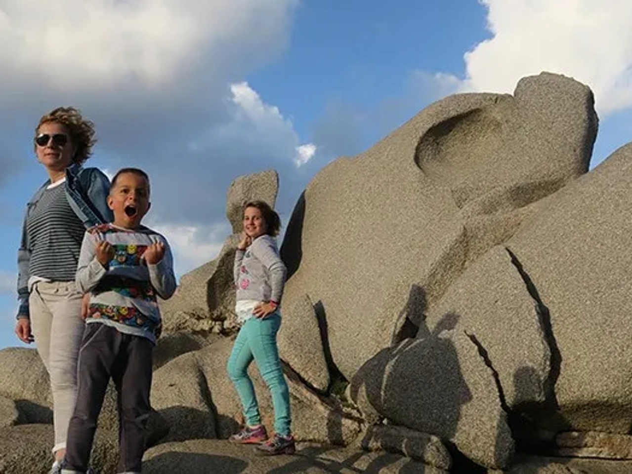 Familia posando en rocas, disfrutando de un día al aire libre.